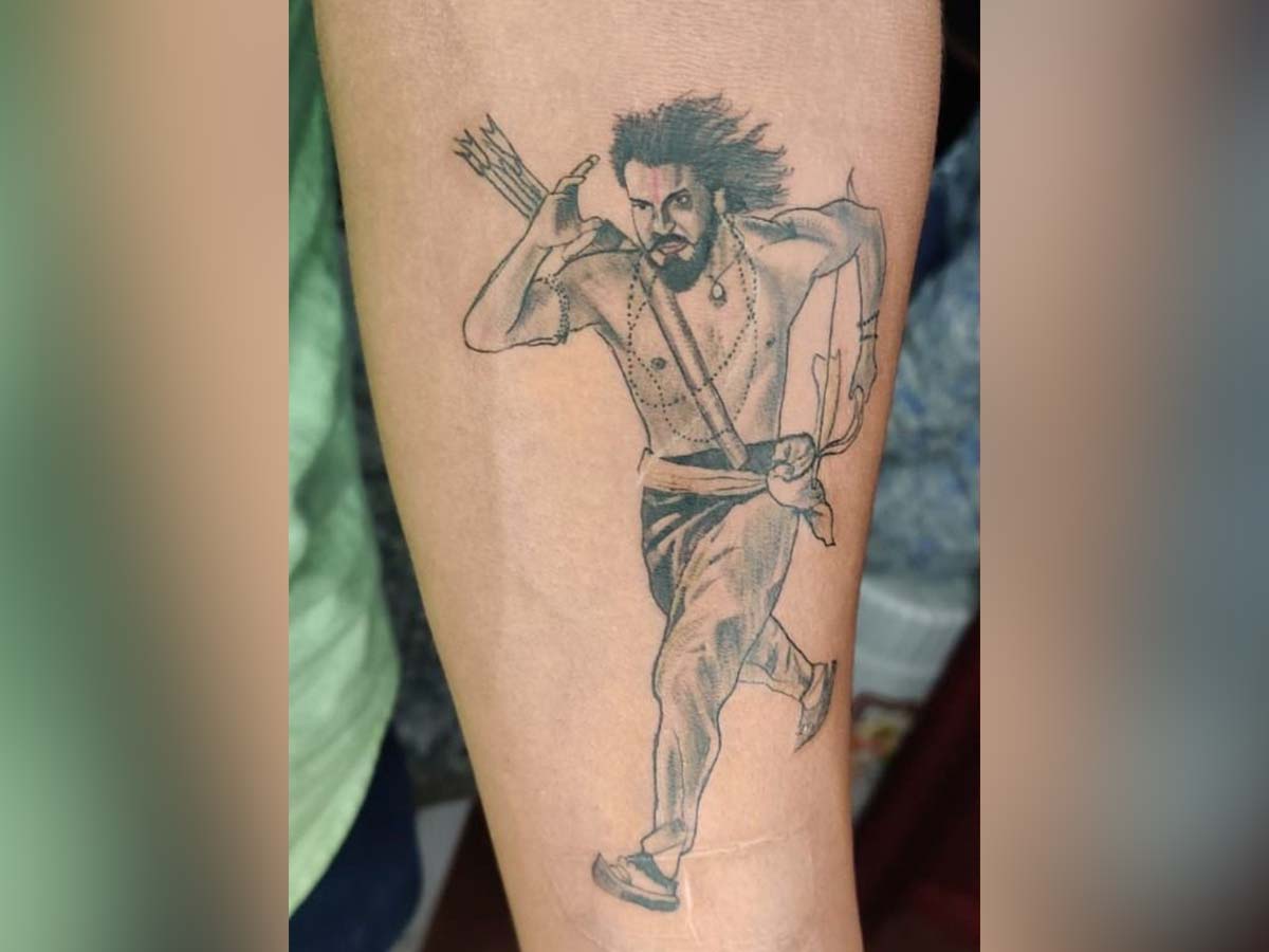 A fan inks Ram Charan tattoo in RRR avatar on his arm